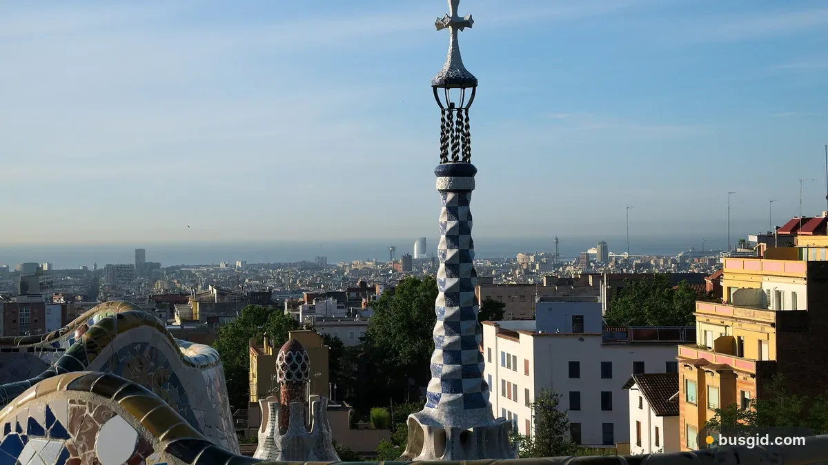 Мозаїчна лава і вежа з хрестом на терасі парку Гуель, унизу панорама Барселони до самого моря