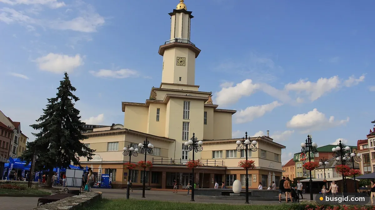 Ратуша Івано-Франківська з високою вежею на площі Ринок літнього дня, ліхтарі з квітами та ялина біля входу