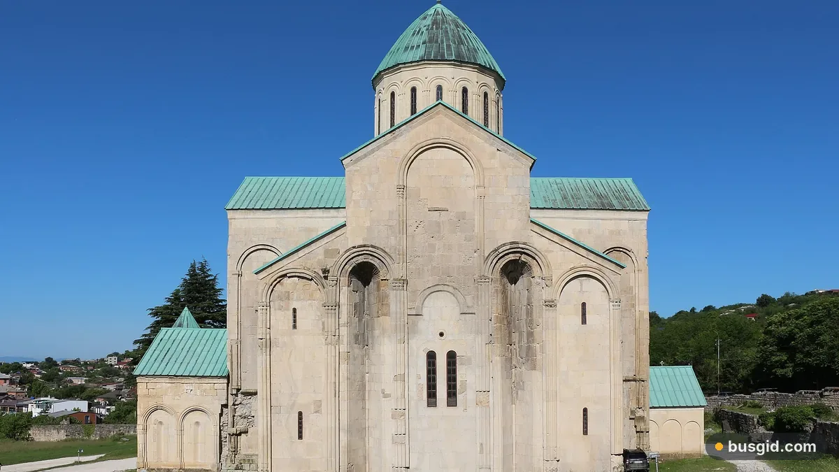 Собор Баграти в Кутаиси из светлого камня с зелёным куполом на холме Укимериони под ясным голубым небом