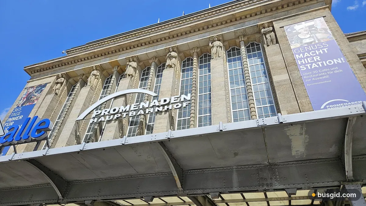 Фасад главного вокзала Лейпцига с надписью Promenaden Hauptbahnhof на фоне голубого неба