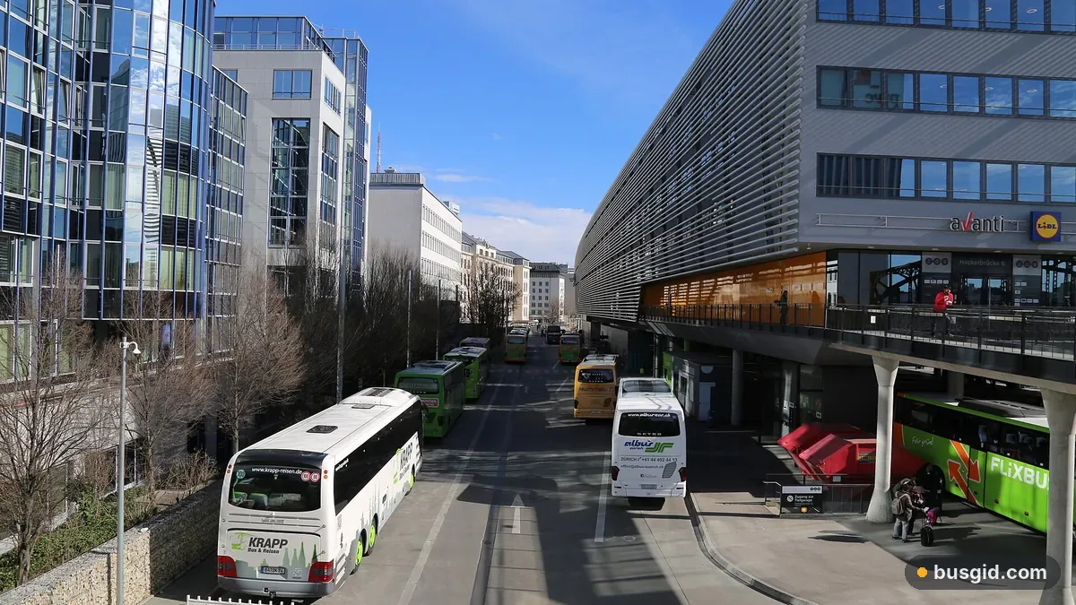 Междугородние автобусы на перронах центрального автовокзала ZOB в Мюнхене у современного здания с галереей и магазинами