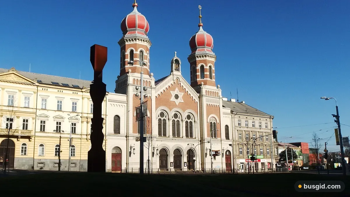 Велика синагога в Пльзені з двома вежами під червоними цибулястими куполами на тлі синього неба в сонячний день