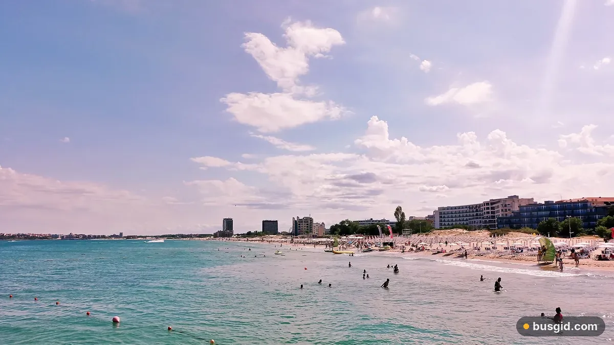 Бірюзове мілке море та довгий піщаний пляж Сонячного Берега з парасолями й рядом готелів уздовж узбережжя