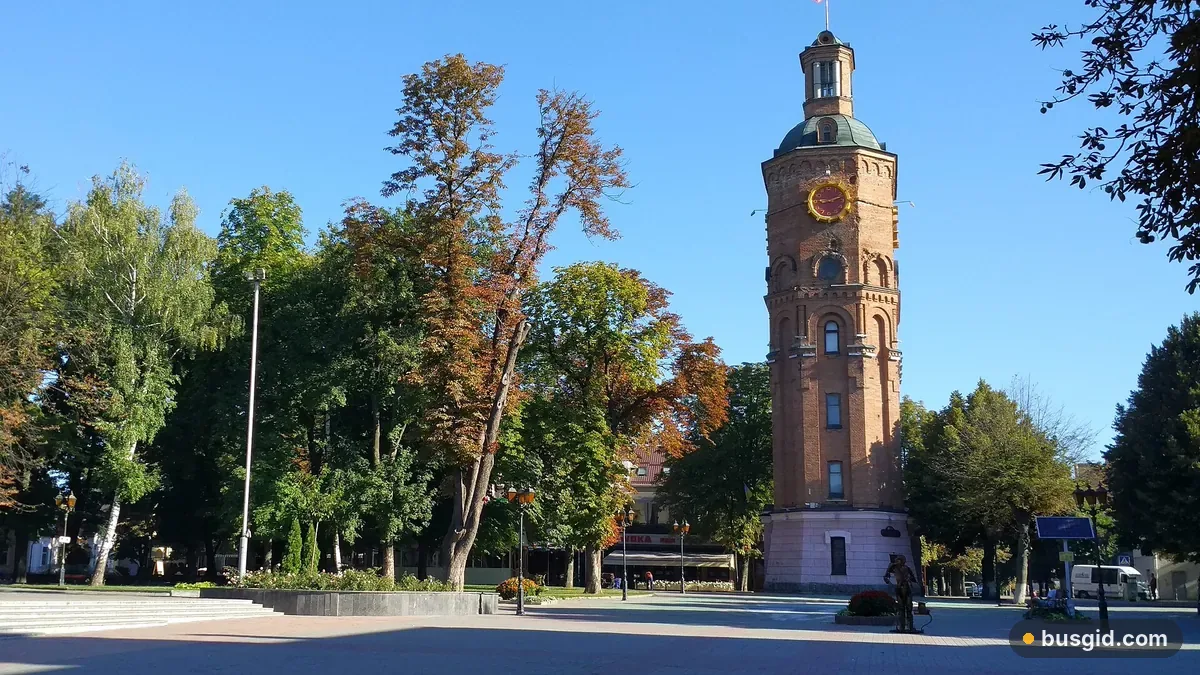 Кирпичная водонапорная башня с часами в центре Винницы среди осенних деревьев на улице Грушевского